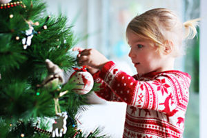 Kleines Mädchen schmückt einen Weihnachtsbaum